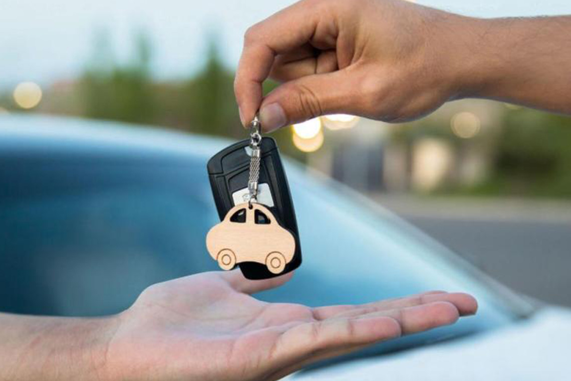 Dettaglio di due mani che si passano un mazzo di chiavi di auto